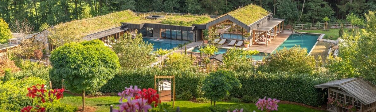 Moderne Poollandschaft mit Wellness-Bereich, umgeben von grünen Bäumen und bunten Blumen