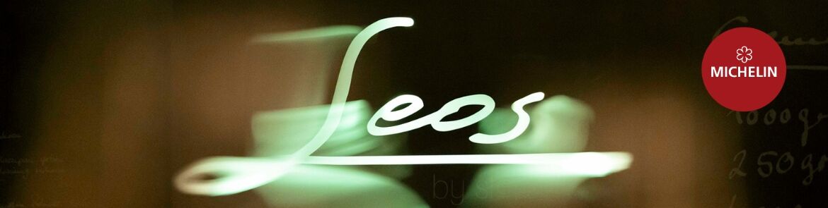 Leuchtschrift "Leos" in grünem Neonlicht vor dunklem Hintergrund
