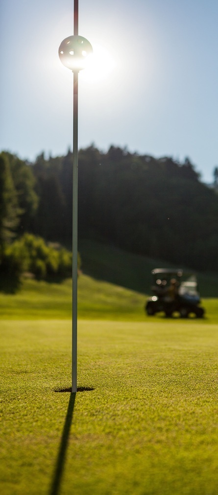 Sonne hinter Pin und Golfloch
